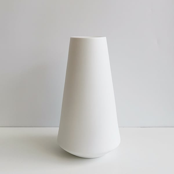 Tall white ceramic vase on a plain background