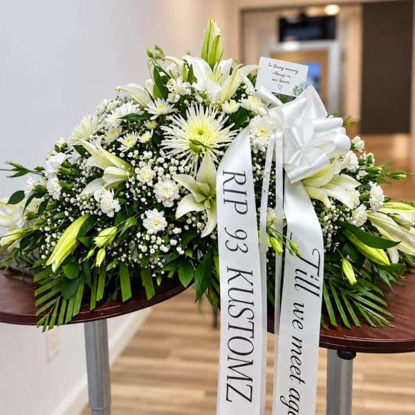 White lilies and chrysanthemums in a funeral spray with ribbons