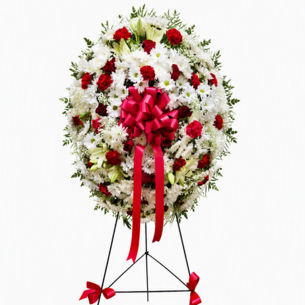 Standing floral wreath of white and red flowers with a pink ribbon bow