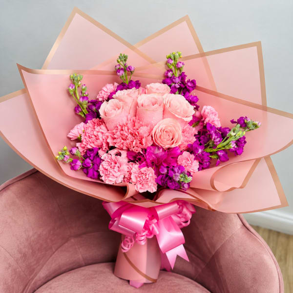 Pink and purple bouquet of roses and carnations wrapped in pink paper