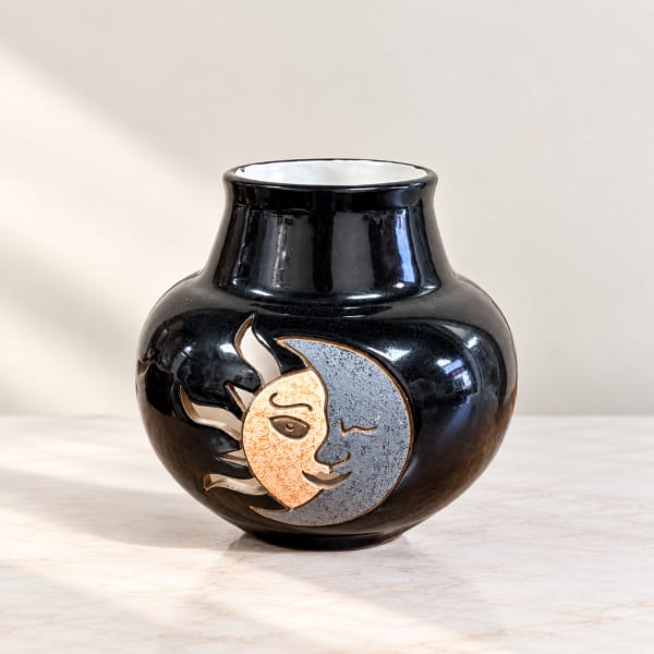 Black ceramic vase with a sun and moon face design