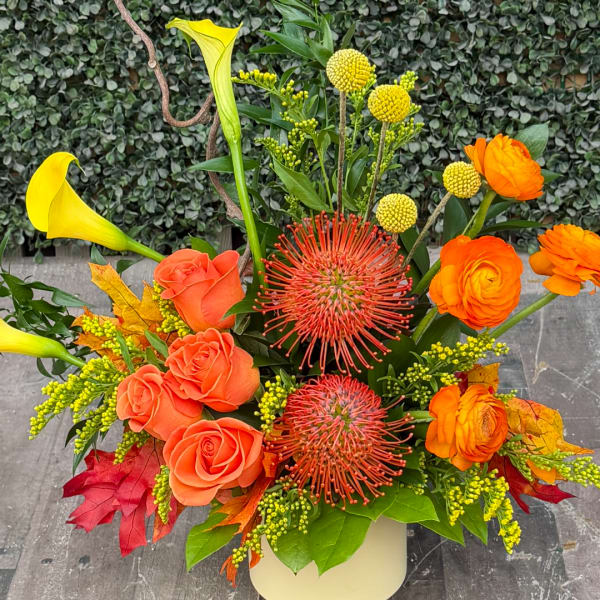 Orange roses and yellow calla lilies in a white vase