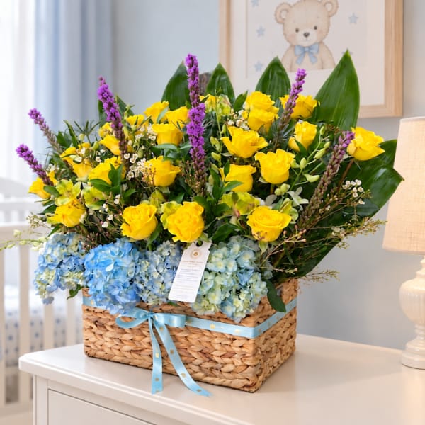 Basket arrangement of yellow roses, blue hydrangeas, and purple spikes