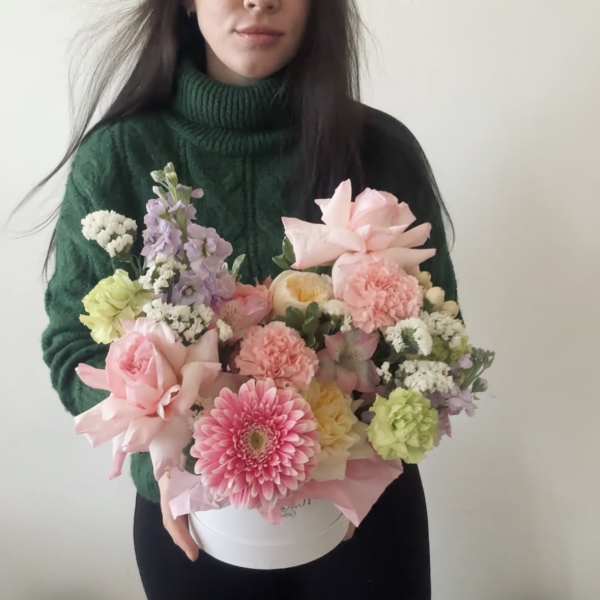 Woman holding a pastel mixed flower arrangement in a white box