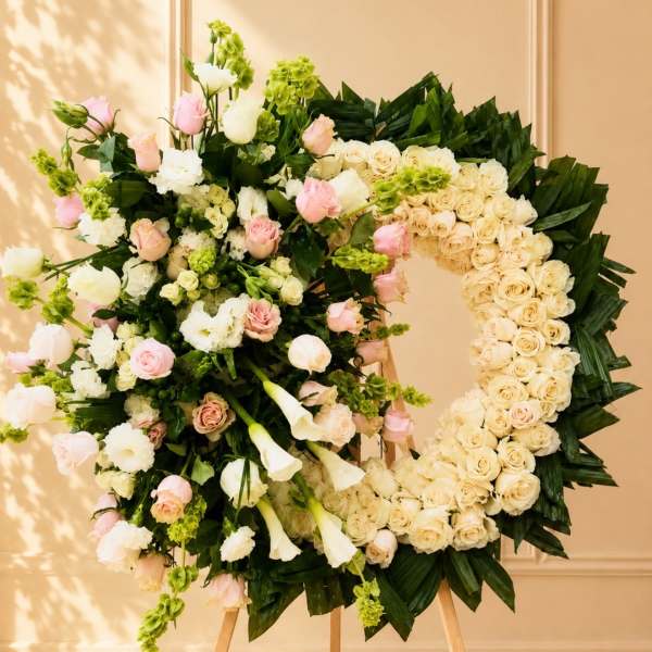 Large floral wreath on an easel with cream, pink, and green flowers