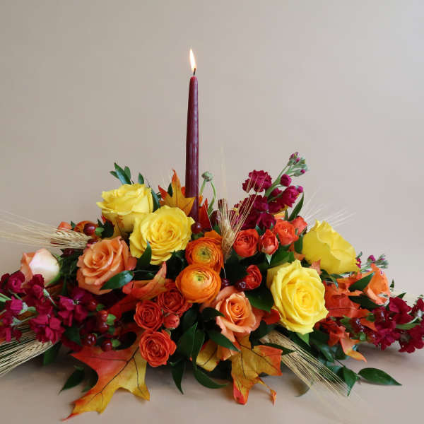 Autumn floral centerpiece with a lit burgundy candle and mixed roses