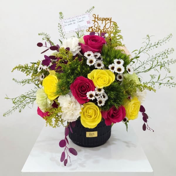 Bright mixed bouquet in a black vase with a birthday topper