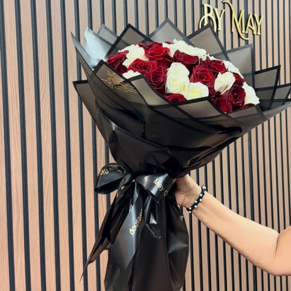 Bouquet of red and white roses wrapped in black paper