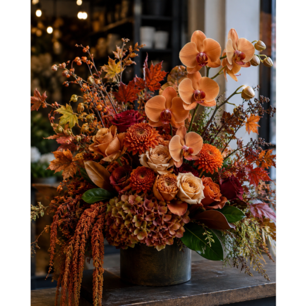 Autumn floral arrangement with orange orchids and roses in a dark vase
