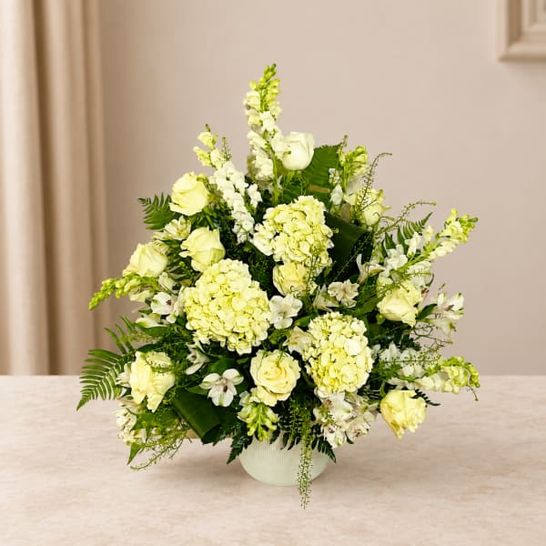 White and pale yellow floral arrangement in a white vase