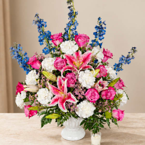 Pink roses, white lilies, and blue flowers in a white vase