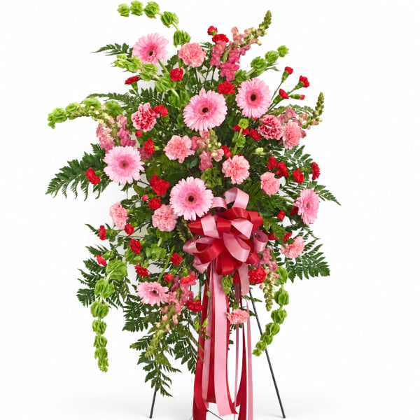 Pink and red floral standing spray with ribbon on a metal easel