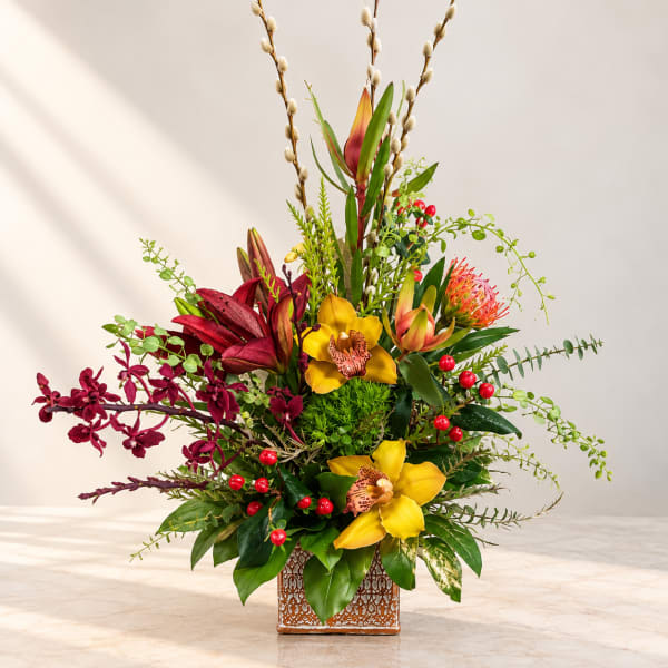 Tall tropical flower arrangement in a patterned square vase
