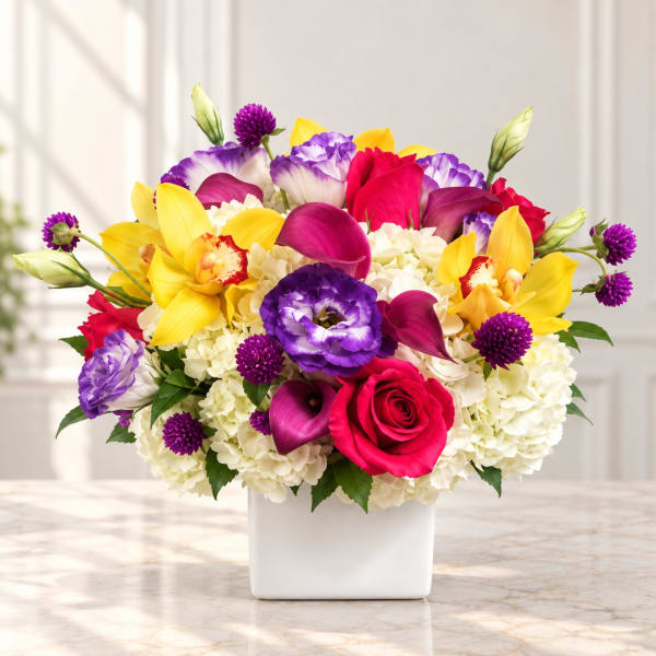 Colorful bouquet with roses, orchids, hydrangeas, and calla lilies in a white vase