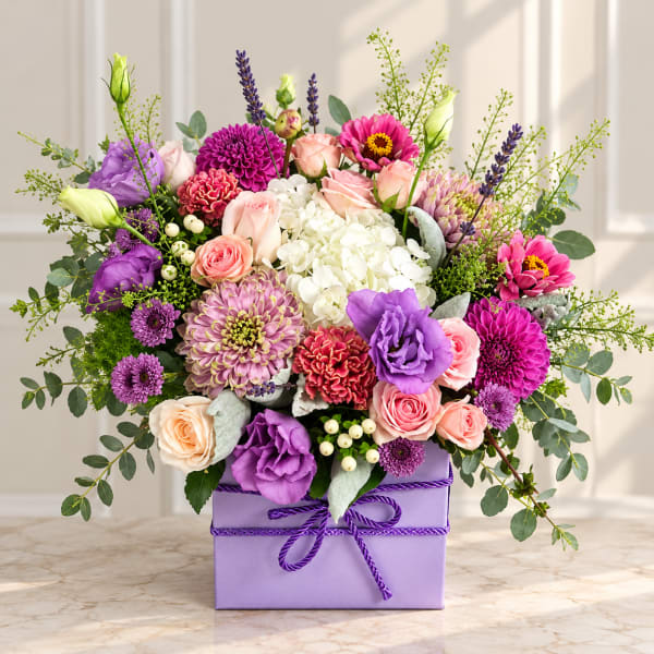 Mixed bouquet of pink, purple, and white flowers in a lavender box