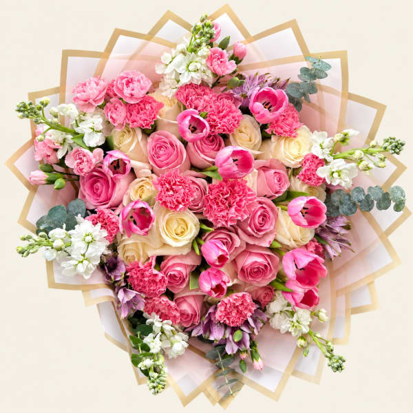 Pink and cream bouquet with roses, tulips, and carnations wrapped in paper