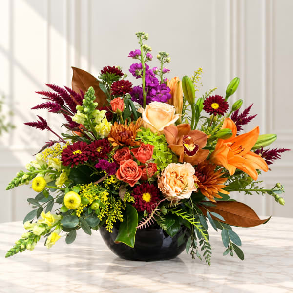 Mixed bouquet in a black bowl vase with orange lilies and purple blooms