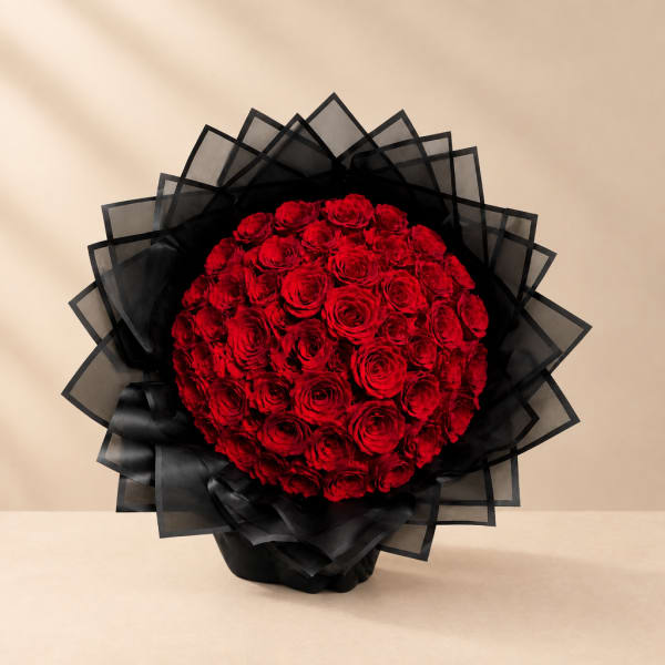 Round bouquet of red roses wrapped in black paper