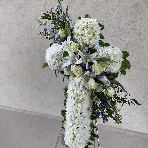 White floral standing spray with lilies, roses, and chrysanthemums on an easel