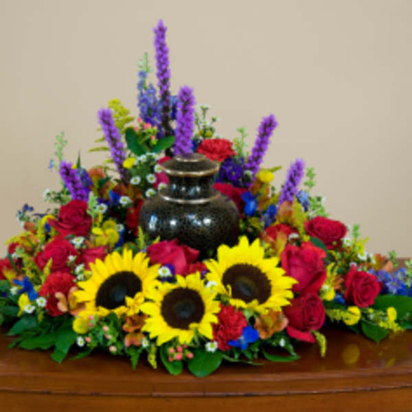 Colorful floral casket spray with sunflowers, red roses, and purple spikes