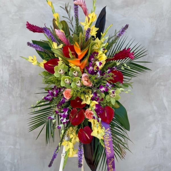 Tall tropical flower arrangement with orchids, anthuriums, and bright mixed blooms