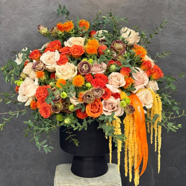 Large mixed bouquet of roses and orange blooms in a black vase