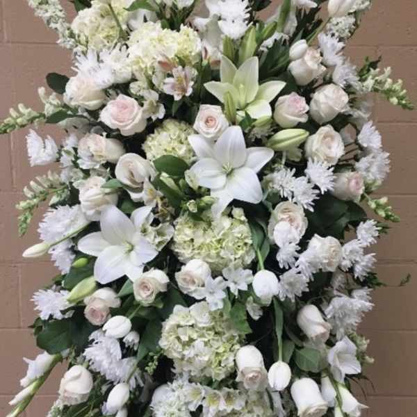 Large white funeral spray with lilies, roses, and hydrangeas