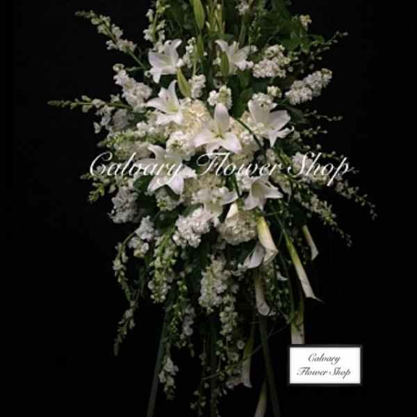 Tall white floral standing spray with lilies and ribbon streamers