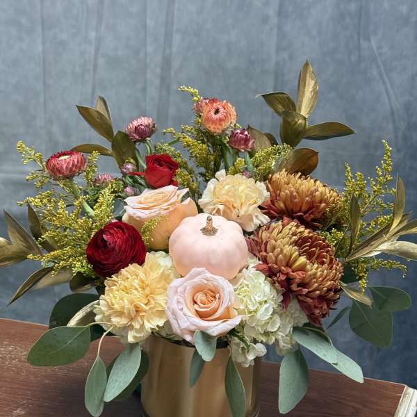 Mixed bouquet in a gold vase with roses, chrysanthemums, and a small pumpkin