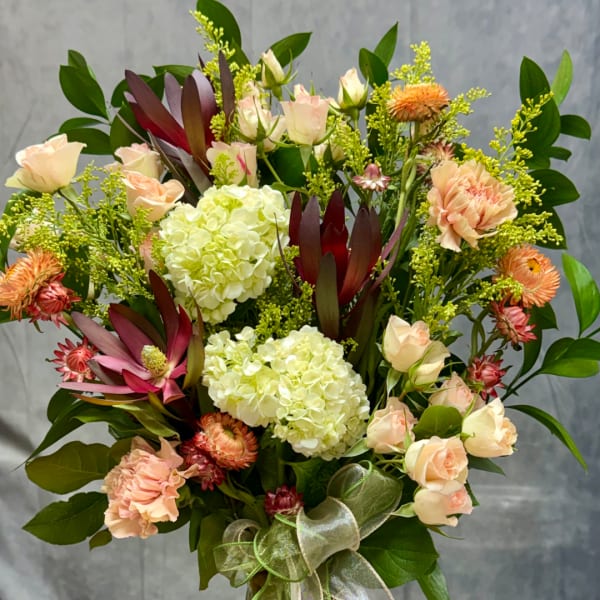 Bouquet of pale roses, hydrangeas, and peach flowers with a ribbon bow