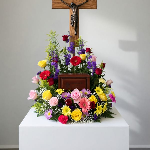 Colorful funeral floral arrangement beneath a wooden crucifix