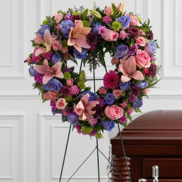 Heart-shaped floral wreath on a stand beside a casket