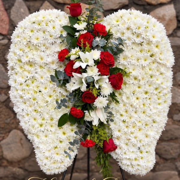 Heart-shaped white floral wreath with red roses and lilies