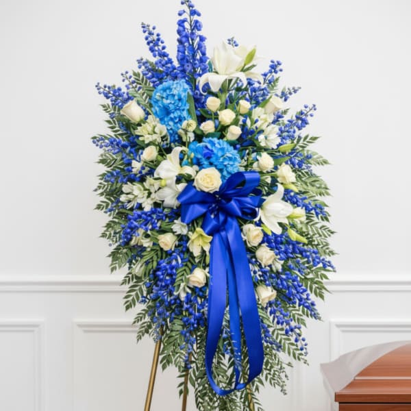 Blue and white funeral spray with a ribbon on an easel