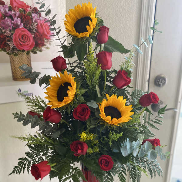 Tall vase arrangement of red roses and sunflowers