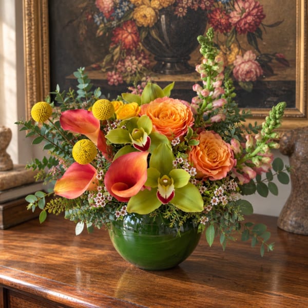 Colorful bouquet with orange roses, calla lilies, and yellow pom flowers in a green vase