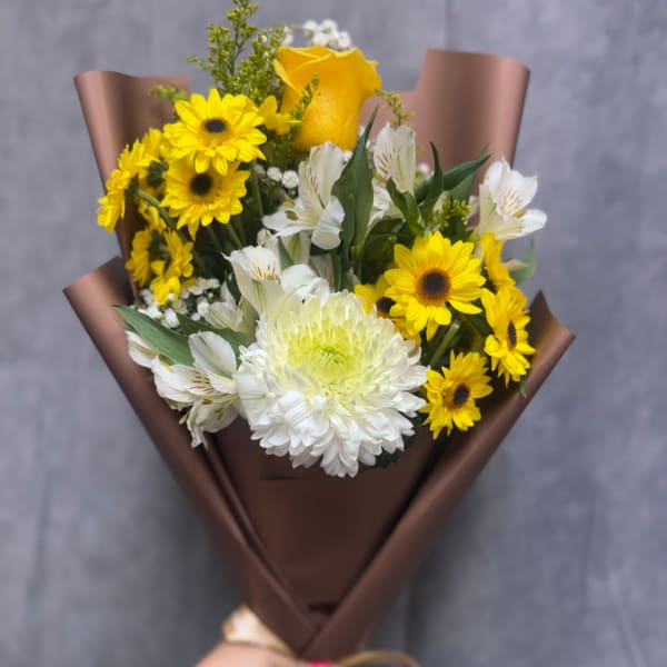 Bouquet of yellow and white flowers wrapped in brown paper