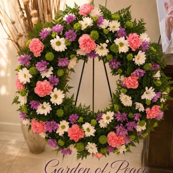 Circular floral wreath with pink, purple, white, and green blooms on a stand