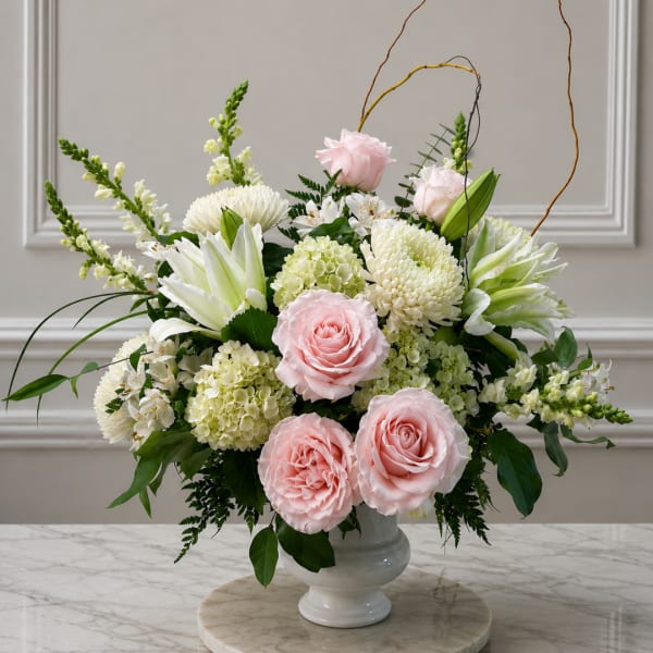 Pink roses and white blooms arranged in a white vase