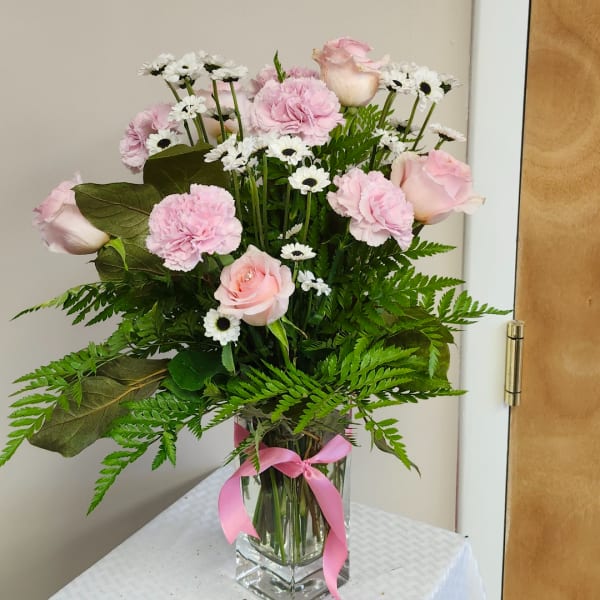 Pink roses and carnations with white daisies in a clear glass vase