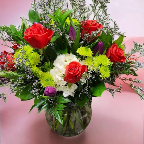 Bouquet of red roses, white hydrangea, and green mums in a glass vase