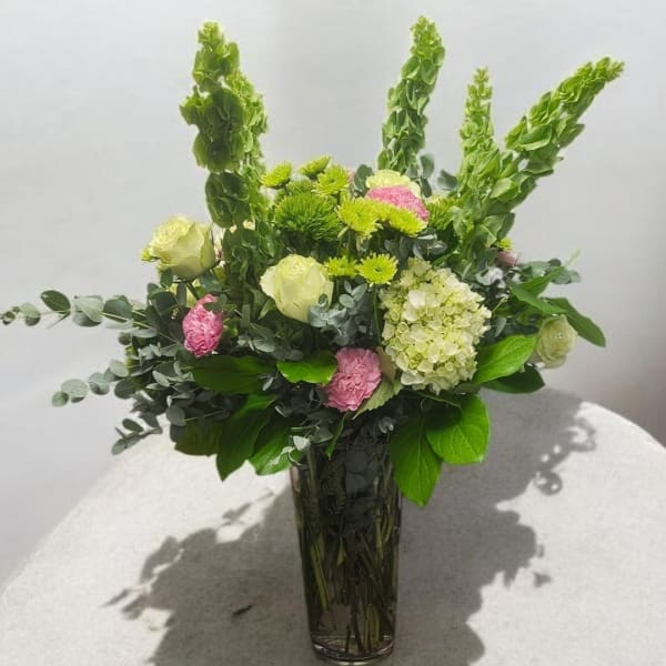 Tall mixed bouquet in a clear glass vase with green and pink flowers