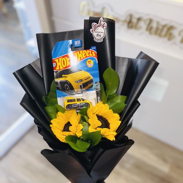 Sunflower bouquet with a Hot Wheels toy car package in black wrap