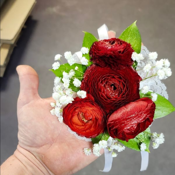 Small red ranunculus corsage with white filler flowers