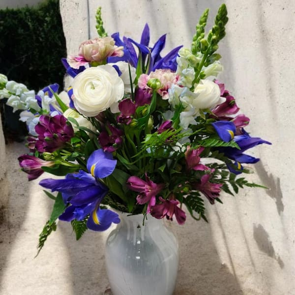 Mixed bouquet of white, purple, and pink flowers in a white vase