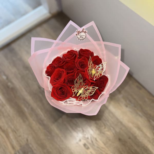 Bouquet of red roses wrapped in pink paper with butterfly decorations