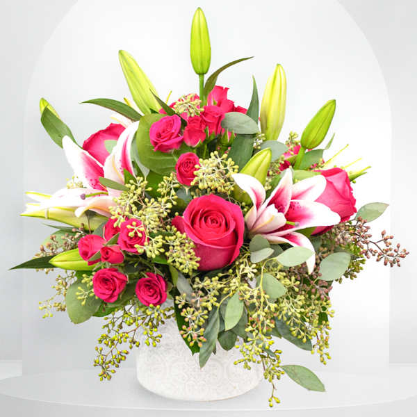 Pink roses and white lilies arranged in a white vase