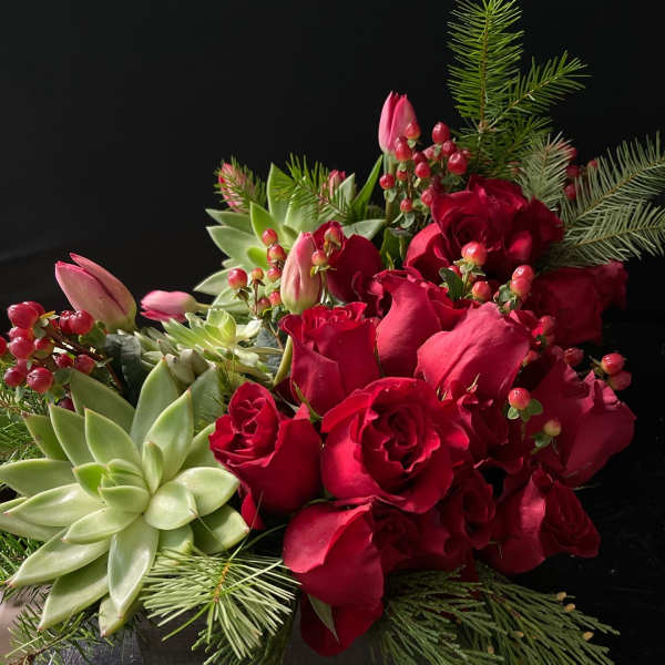 Red roses and pink tulips arranged with succulents in a low container