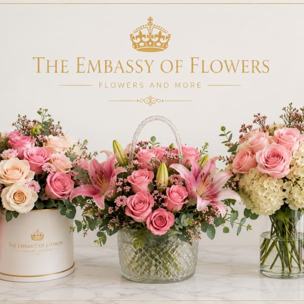 Three pink rose and lily arrangements in containers with a gold logo backdrop