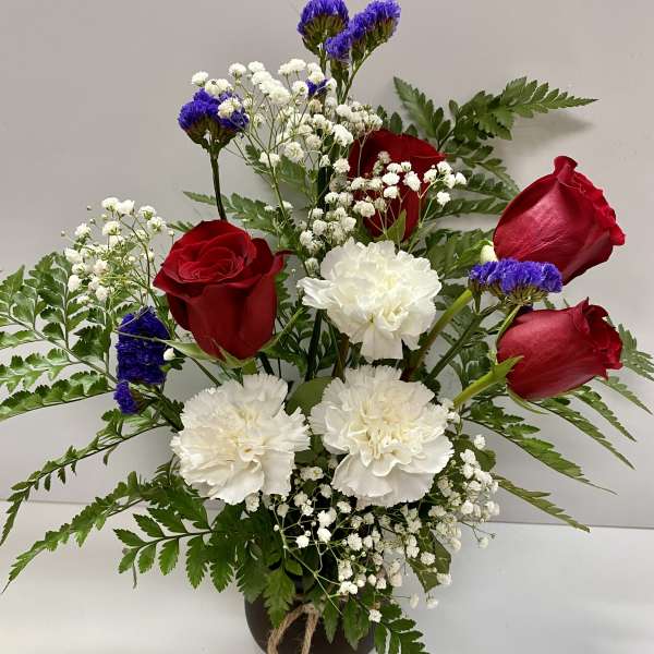 Bouquet of red roses and white carnations in a dark vase